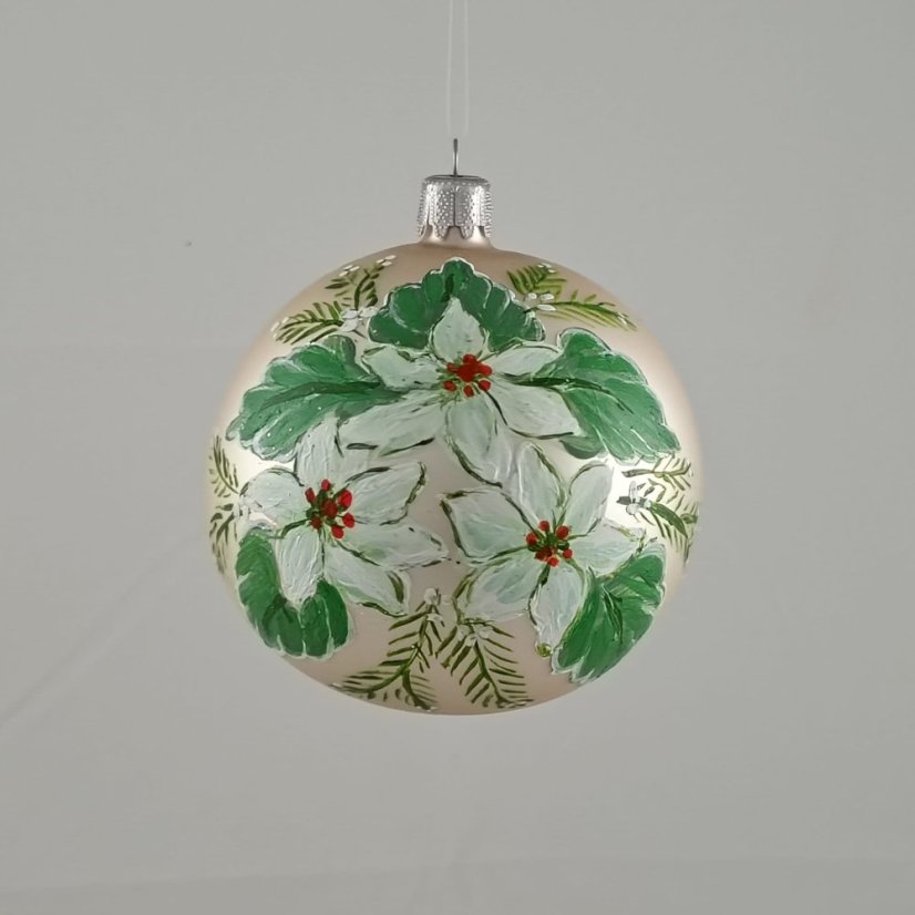 Üveges karácsonyi gömb tejszínszínű háttérrel és fehér karácsonyi virágokkal