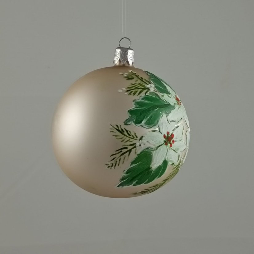 Üveges karácsonyi gömb tejszínszínű háttérrel és fehér karácsonyi virágokkal